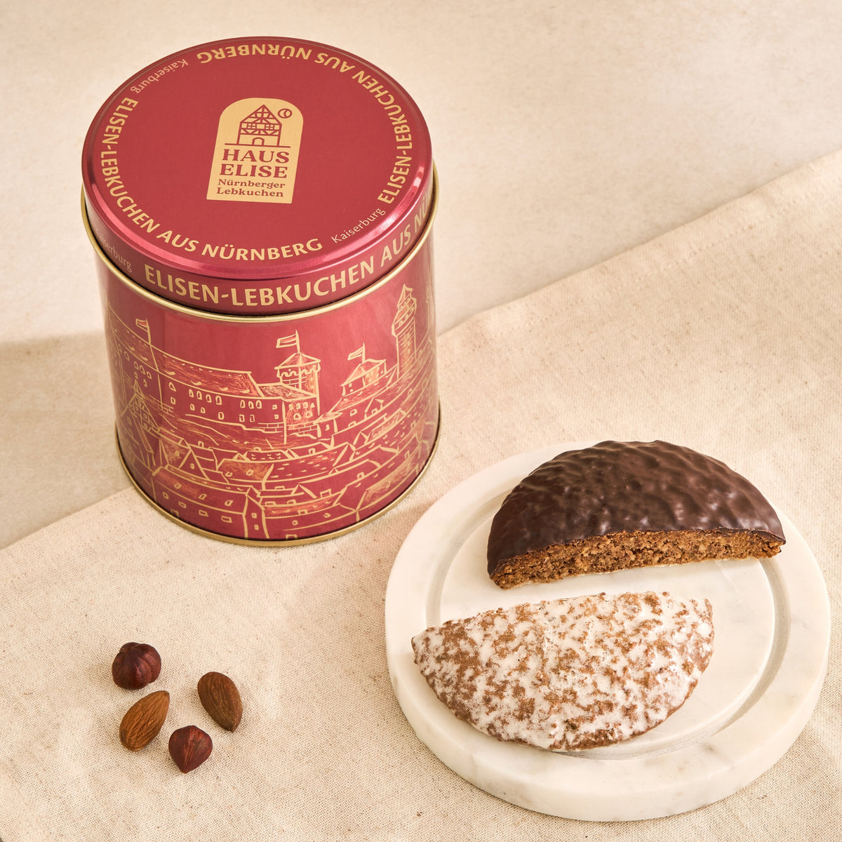 Dose Kaiserburg Rot auf Leinen mit Elisen-Lebkuchen auf Marmorteller und Nüssen