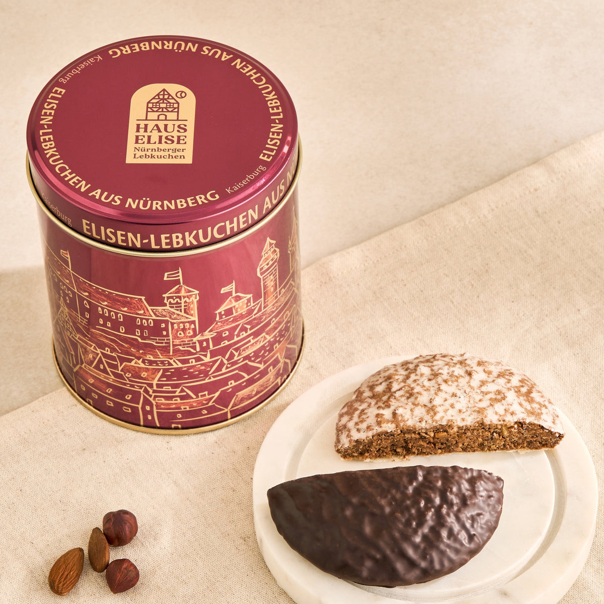Dose Kaiserburg Bordeaux auf Leinen mit Elisen-Lebkuchen auf Marmorteller und Nüssen