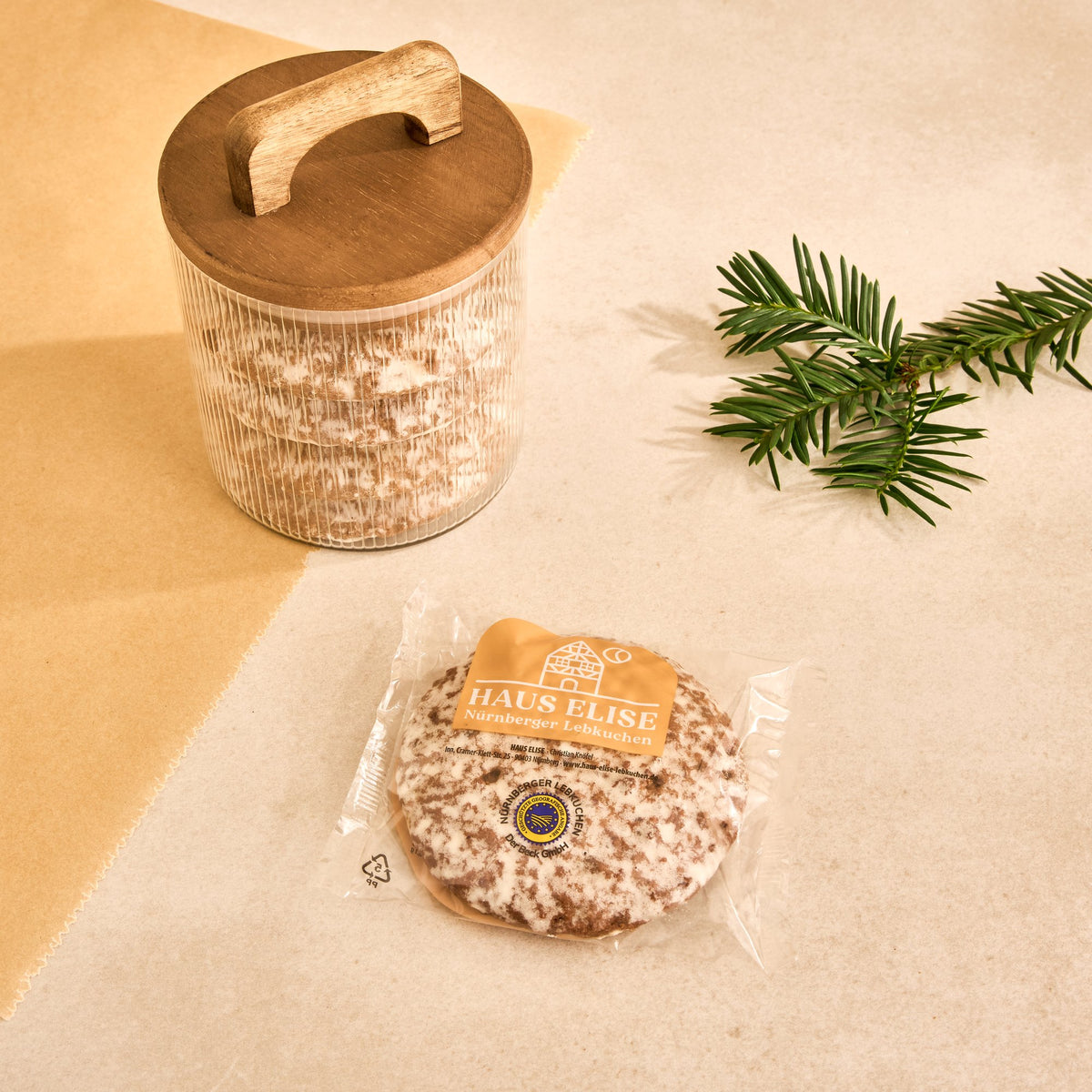 Einzeln in Folie verpackter glasierter HAUS ELISE Elisen-Lebkuchen mit Etikett, daneben ein Vorratsglas mit Lebkuchen
